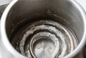 Thick white limescale deposits inside a stainless steel kettle from hard water